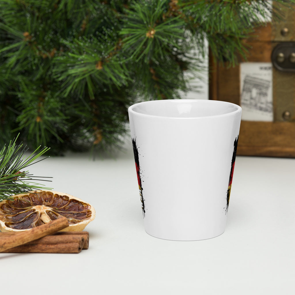 White mug with festive design on a white surface with Christmas decorations.