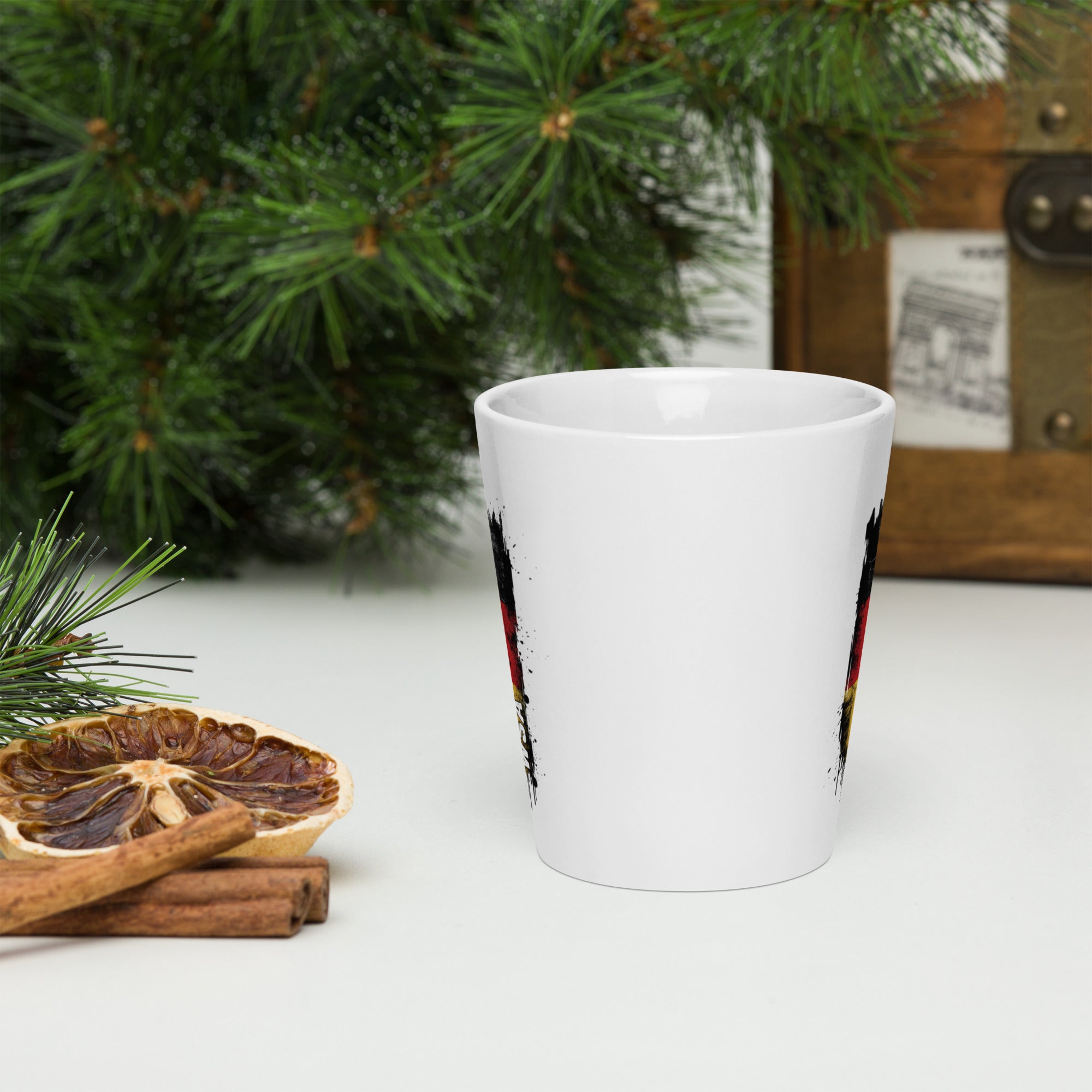 White mug with festive design on a white surface with Christmas decorations.