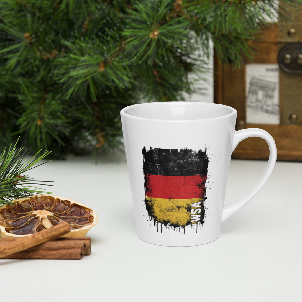 White mug with German flag design on a white surface with Christmas decorations.