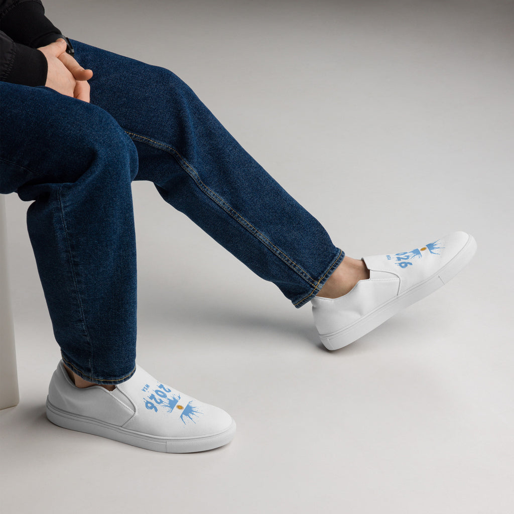Person wearing white sneakers with blue designs and blue jeans on a light gray background