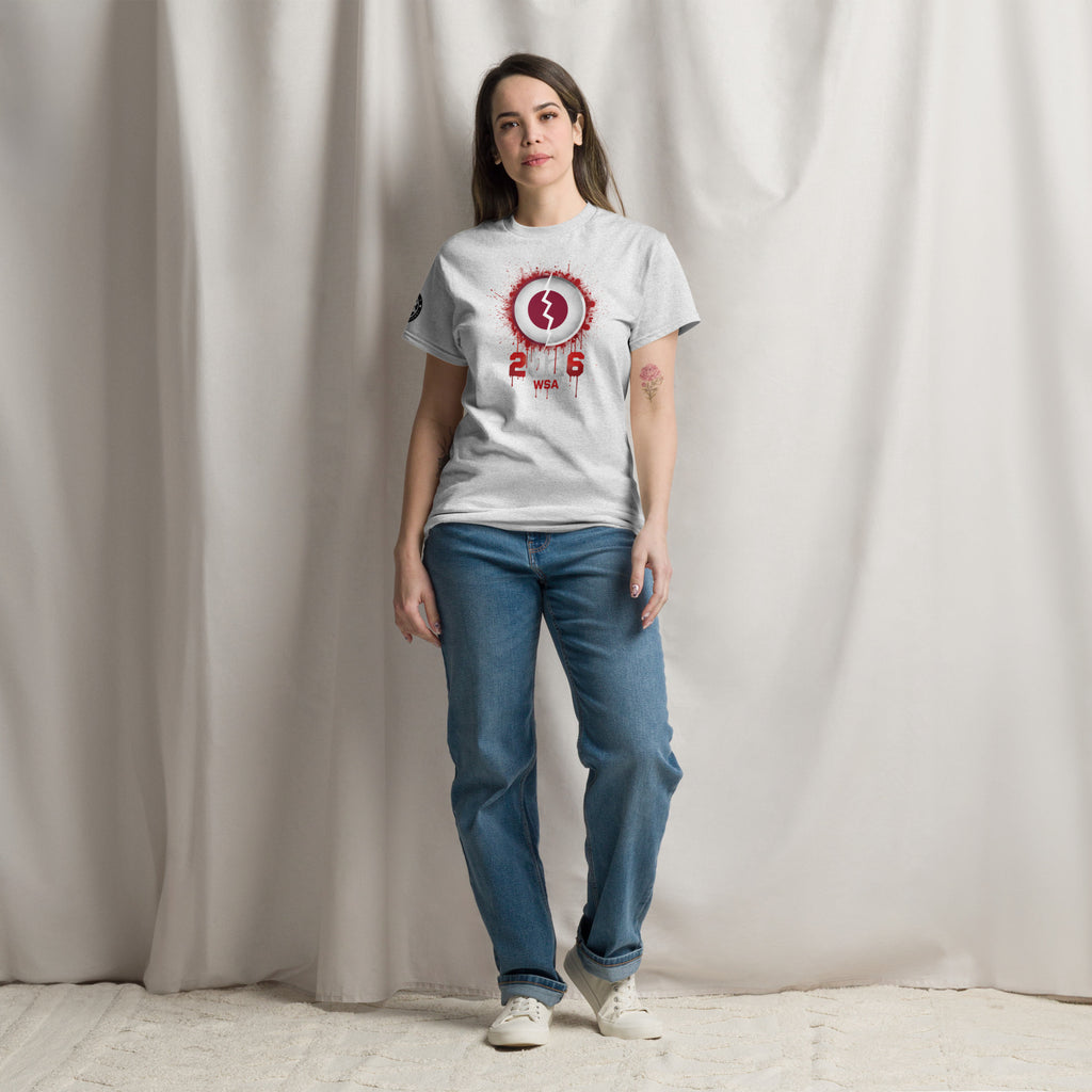 Person wearing a white t-shirt with a red and black design and blue jeans against a plain background