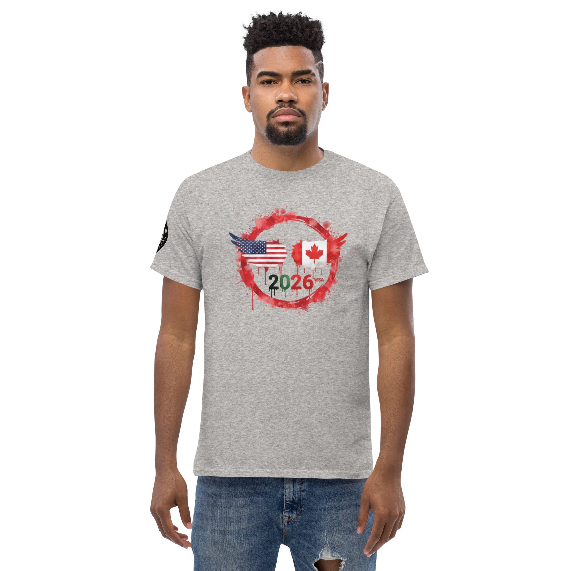 Man wearing a gray t-shirt with a graphic design featuring an American flag, Canadian flag, and the year 2026 on a white background.