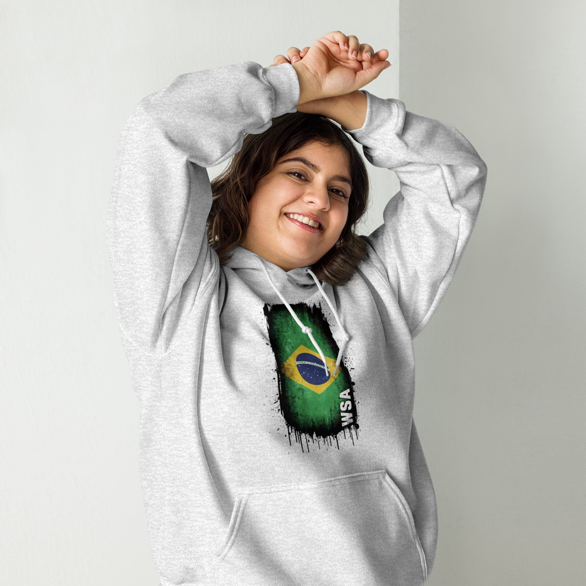 Person wearing a gray hoodie with a Brazilian flag design on a plain background