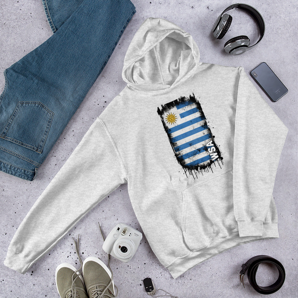 Gray hoodie with a flag design on a gray surface with jeans, shoes, and accessories.