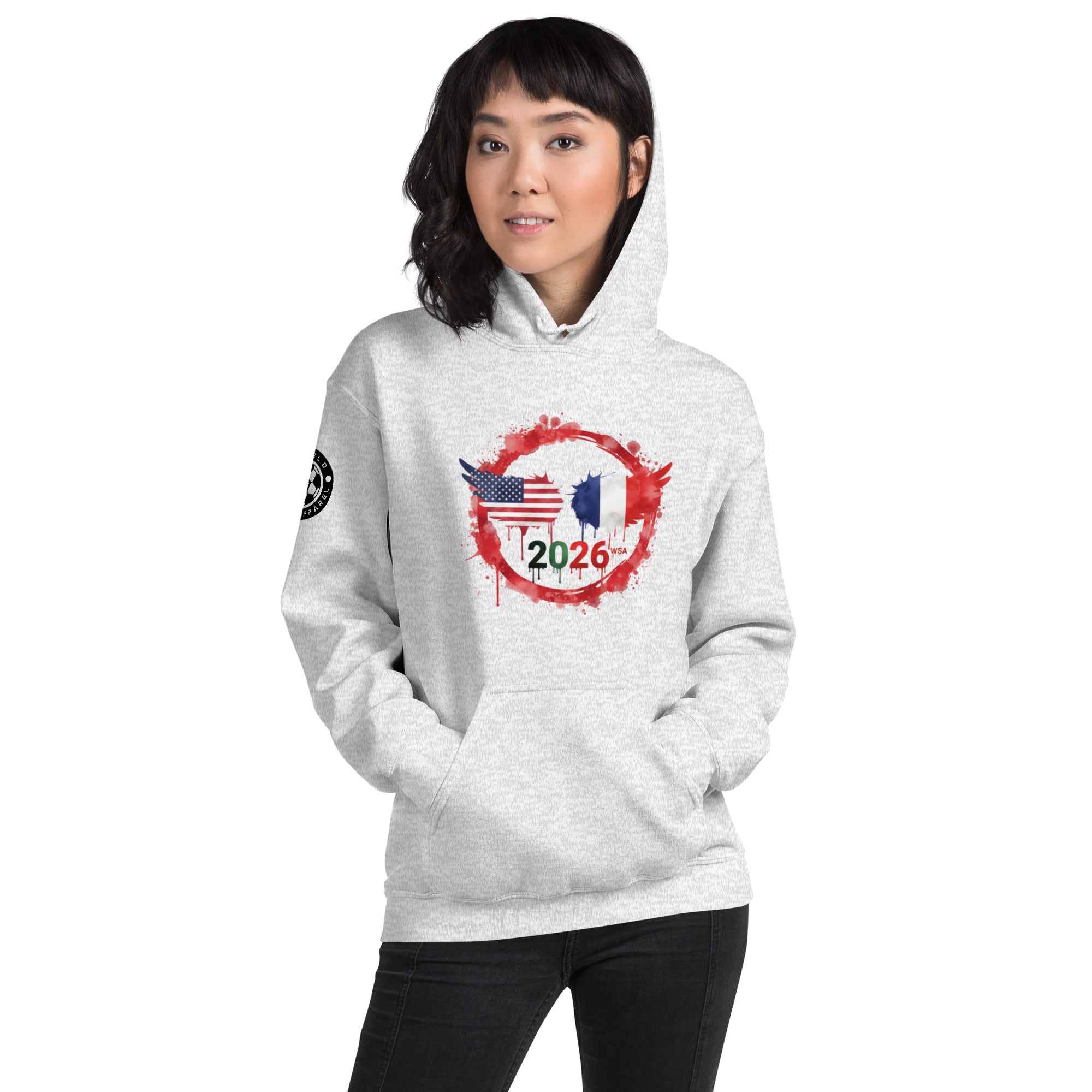 Person wearing a white hoodie with a design featuring the American and French flags and the number 2026 on a white background.