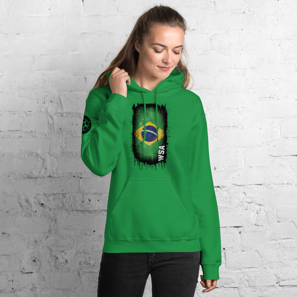 Person wearing a green hoodie with a Brazilian flag design against a white brick wall.