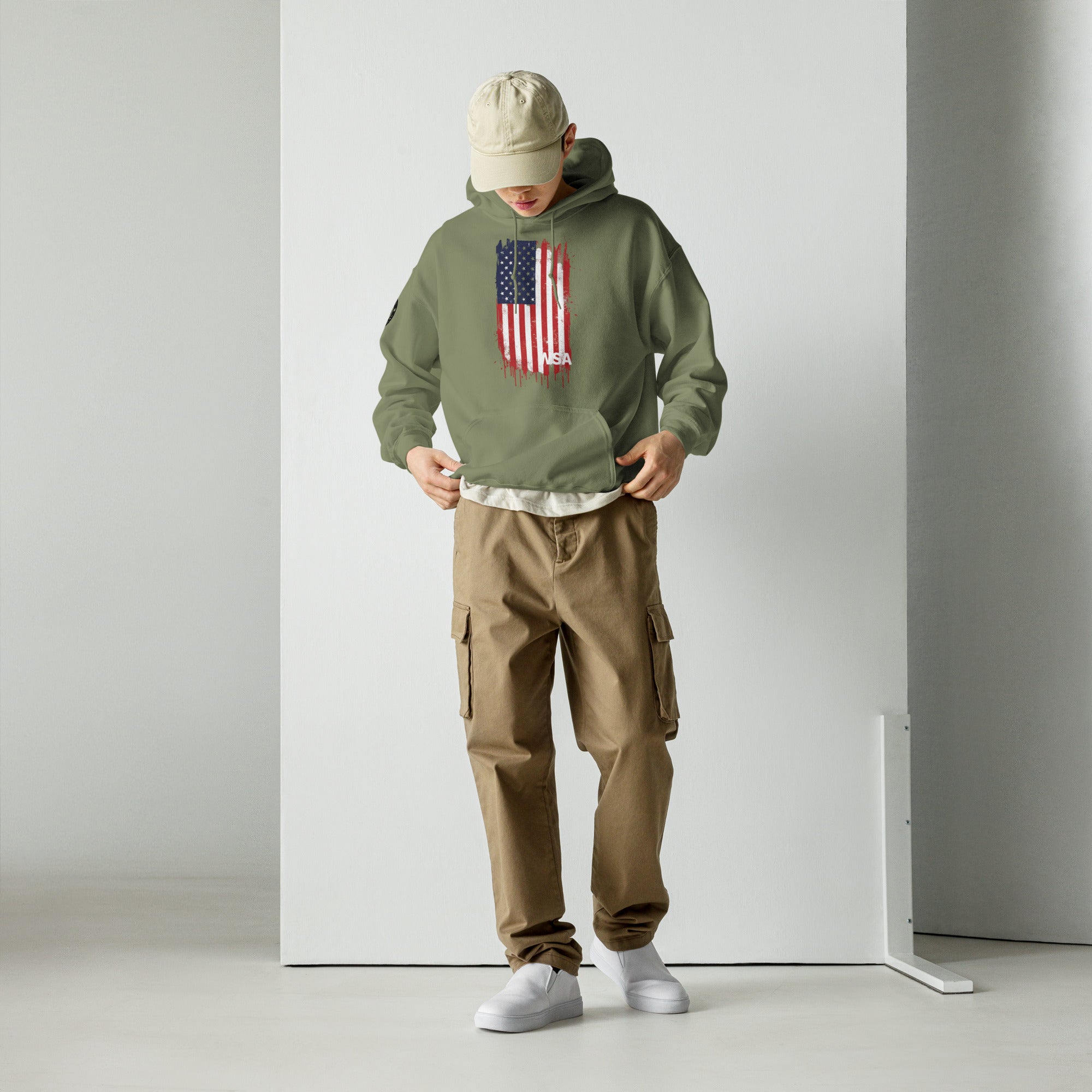 Person wearing a green hoodie with an American flag design and brown cargo pants against a white background