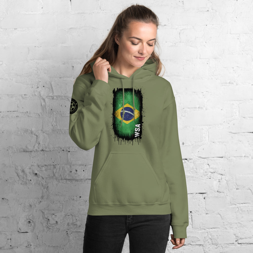 Person wearing a green hoodie with a Brazilian flag design against a white brick wall.