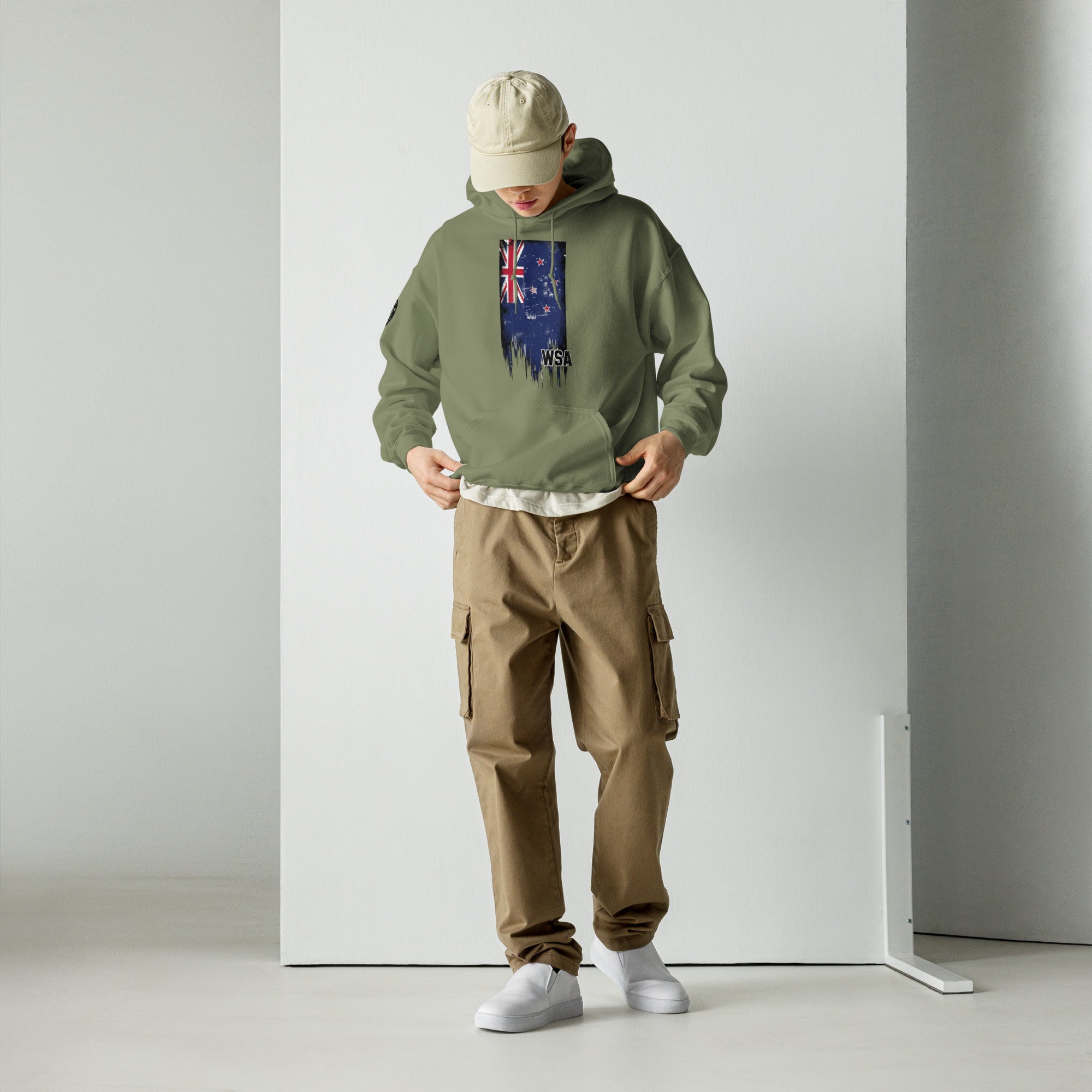 Person wearing a green hoodie with a flag design and brown cargo pants against a white background