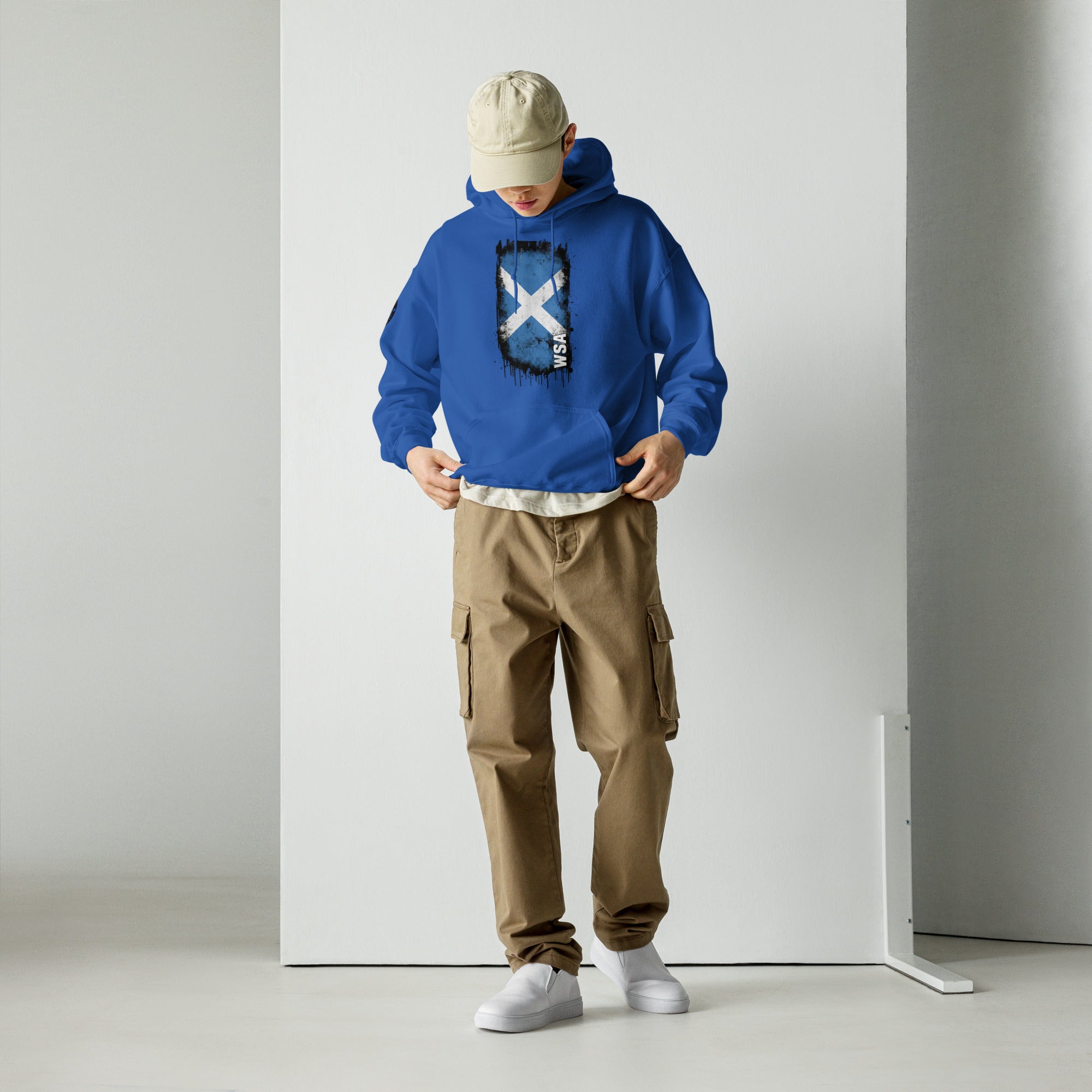 Person wearing a blue hoodie with a logo and brown cargo pants against a white background