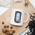 White mug with a flag design on a wooden board with nuts and spider decorations.