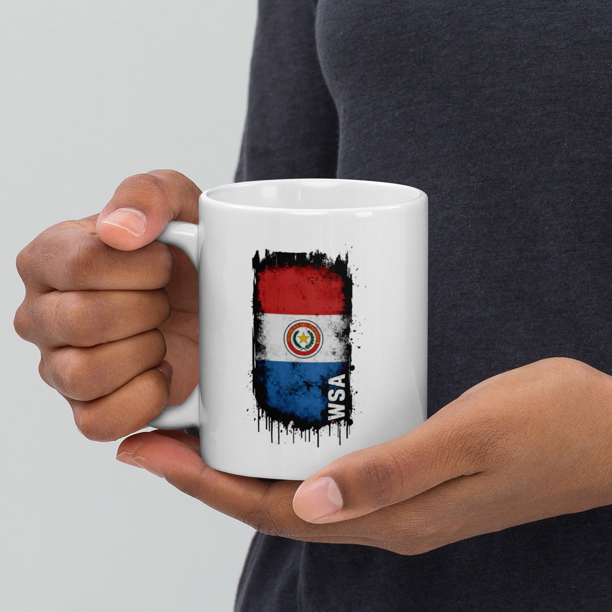 Person holding a white mug with a flag design and 'WASA' text.