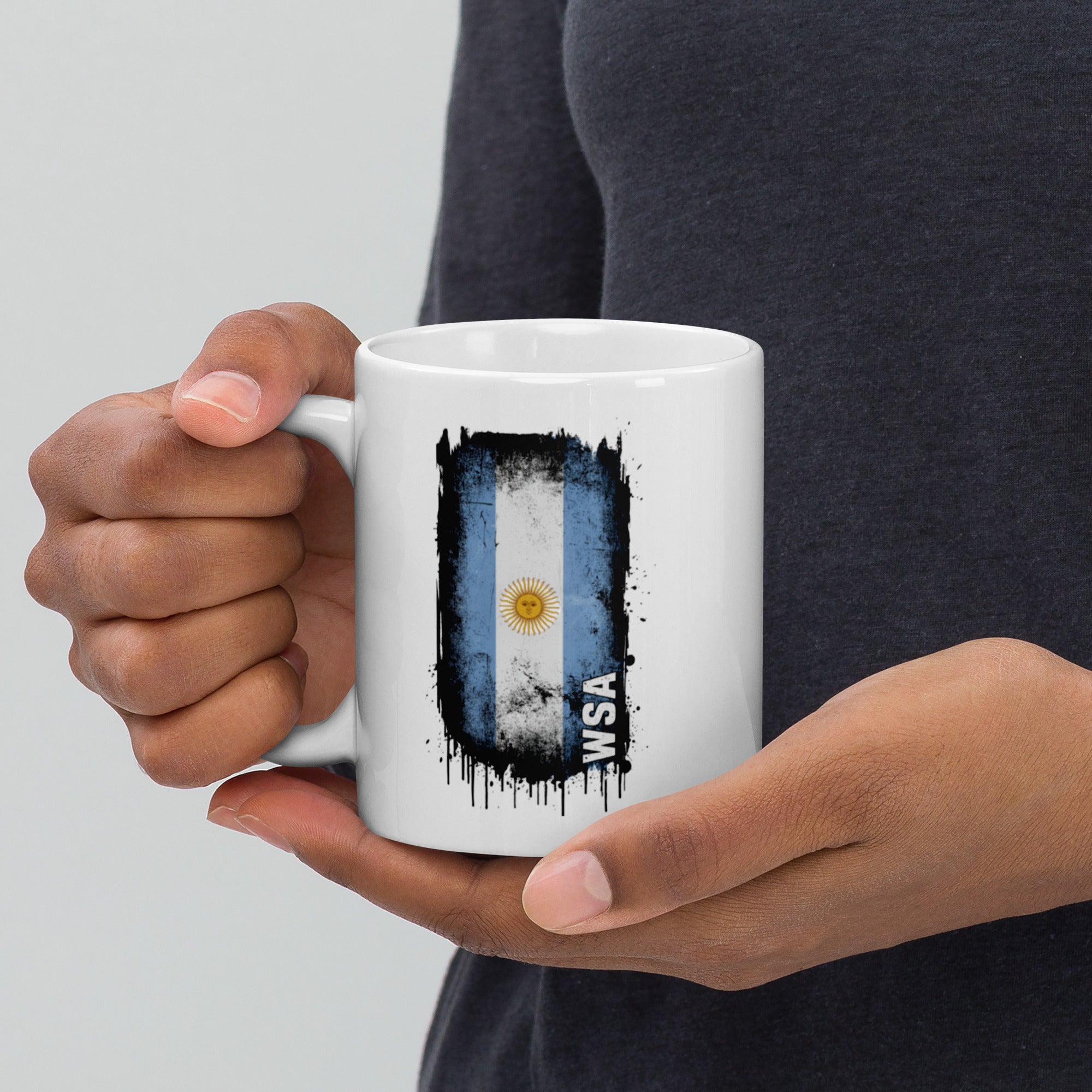 Person holding a white mug with an Argentina flag design and 'WSA' text.