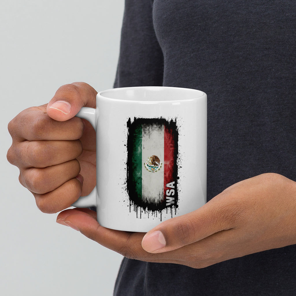 Person holding a white mug with a Mexican flag design on a light gray background