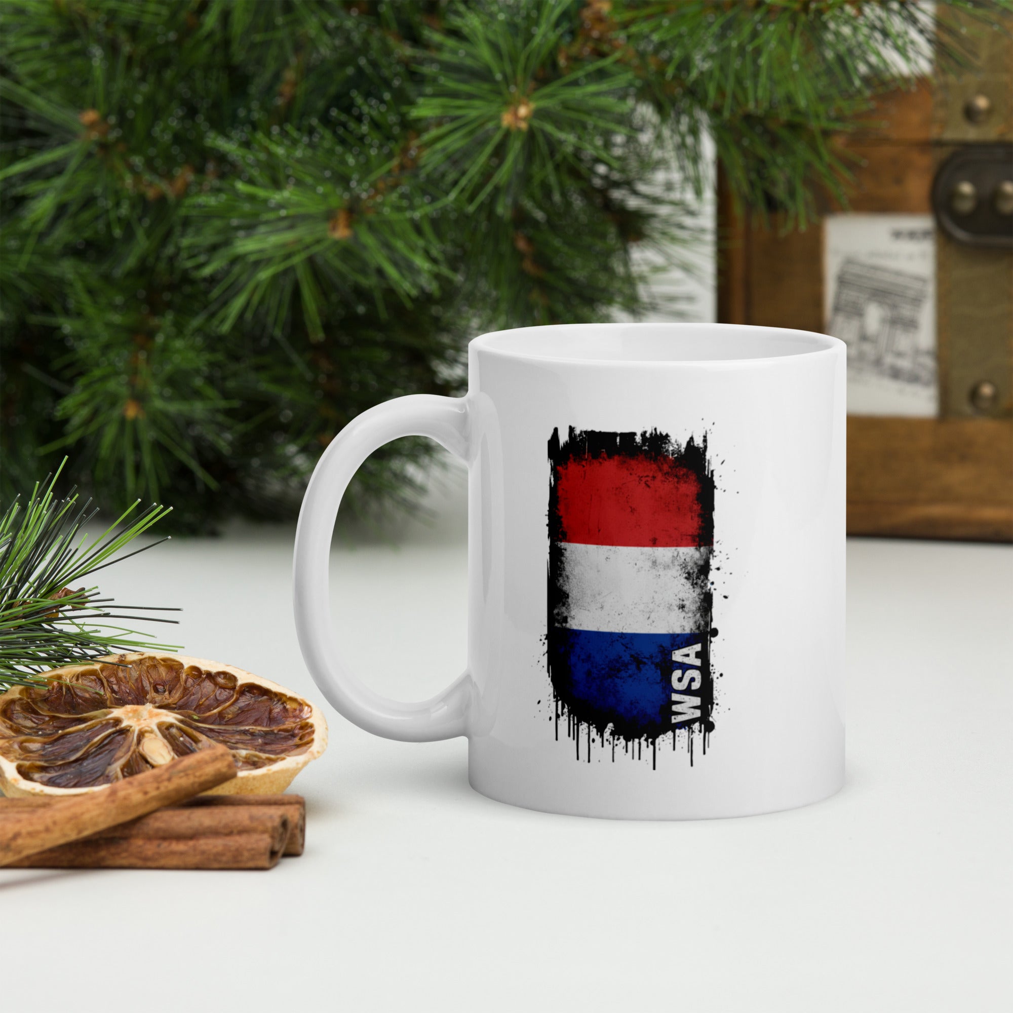 White mug with a colorful design on a table with Christmas decorations