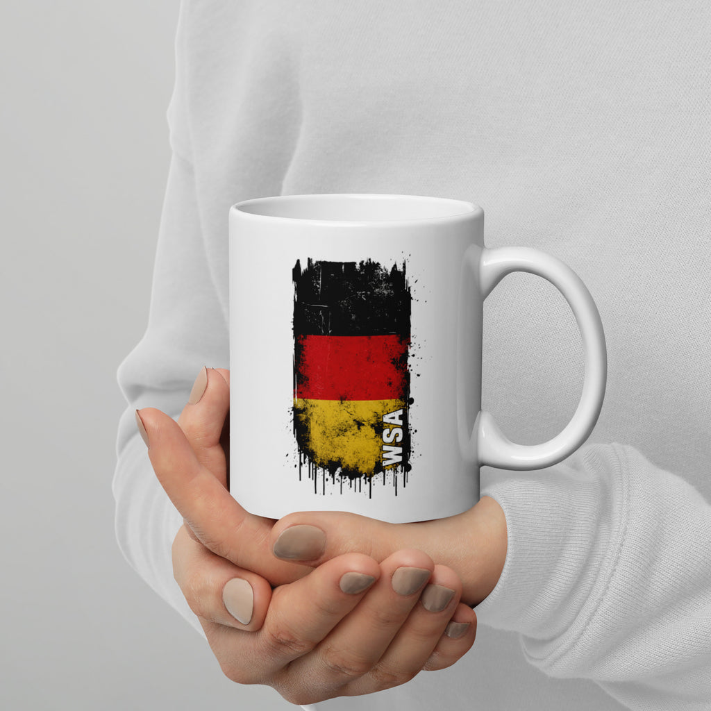 Person holding a white mug with a black, red, and yellow design and 'WSA' text.