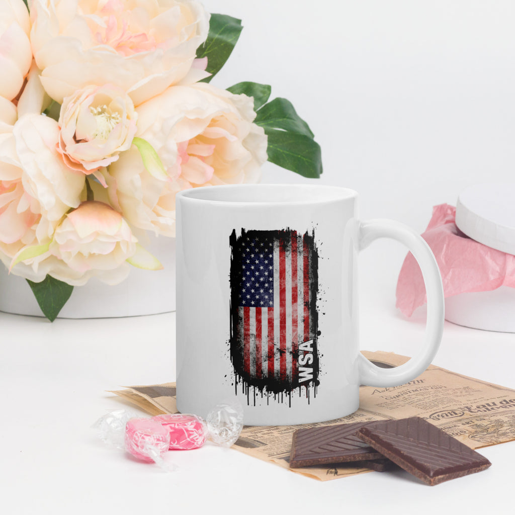 White mug with American flag design on a table with flowers and snacks