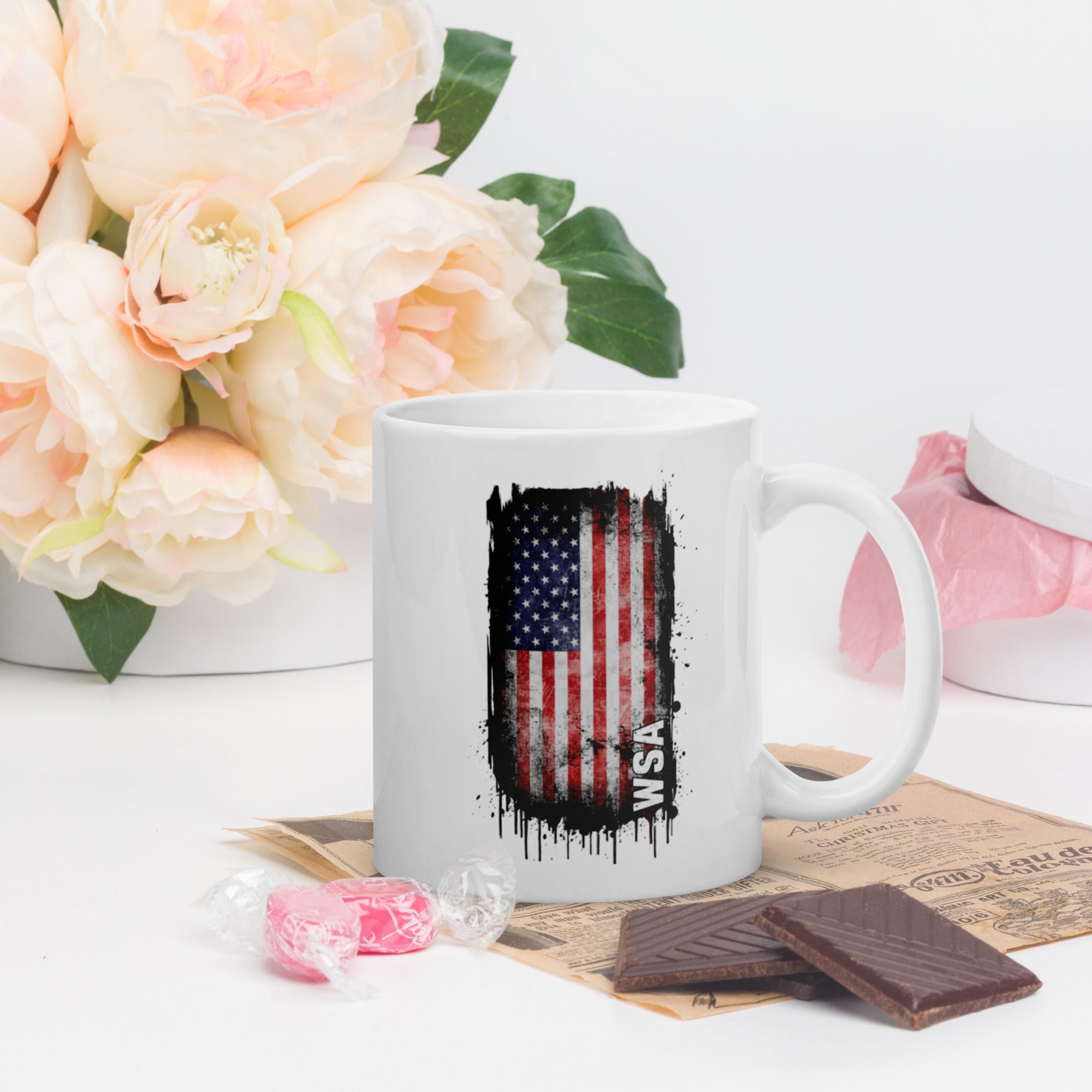 White mug with American flag design on a table with flowers and snacks