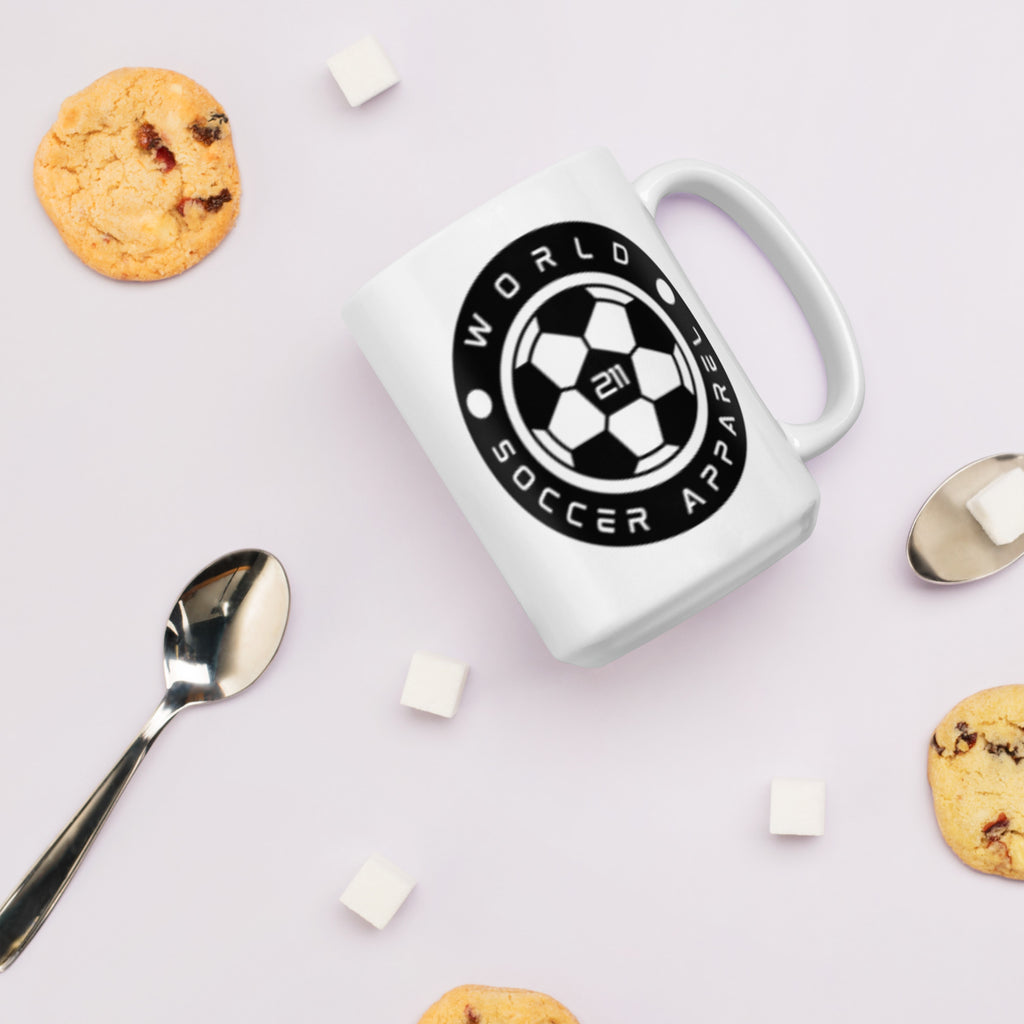 White mug with a black logo on a light surface with cookies and spoons.