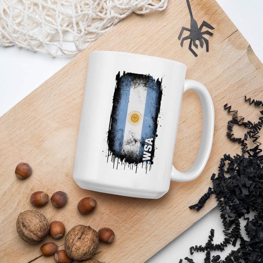 White mug with Argentina flag design on a wooden board with nuts and decorative elements.