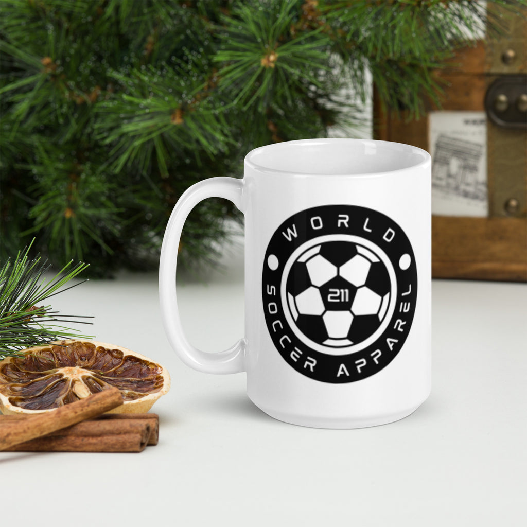 White mug with 'World Soccer Apparel' logo on a table with Christmas decorations.