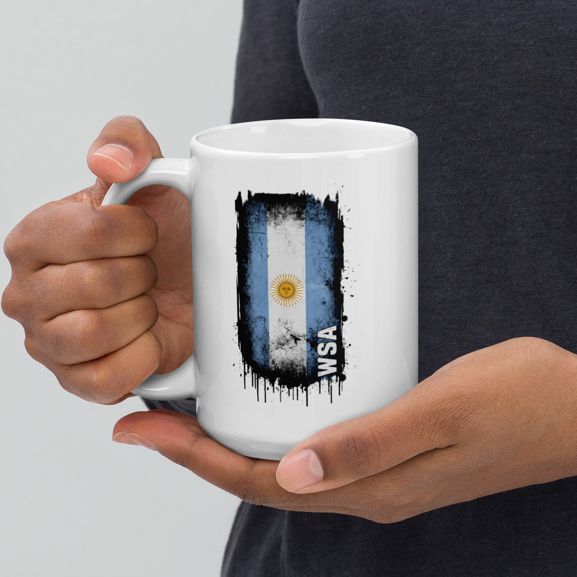 Person holding a white mug with an Argentina flag design and 'WSA' text.