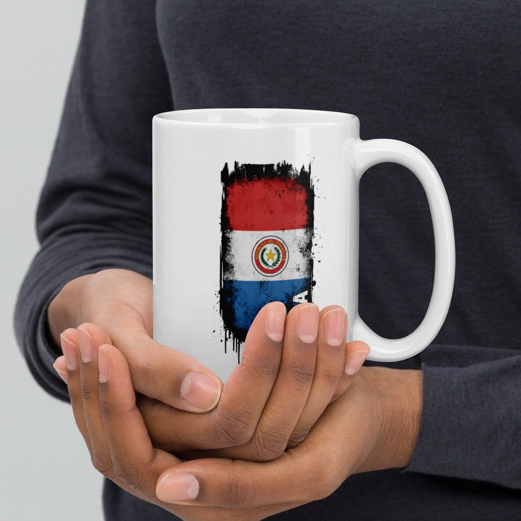 Person holding a white mug with a flag design against a gray background