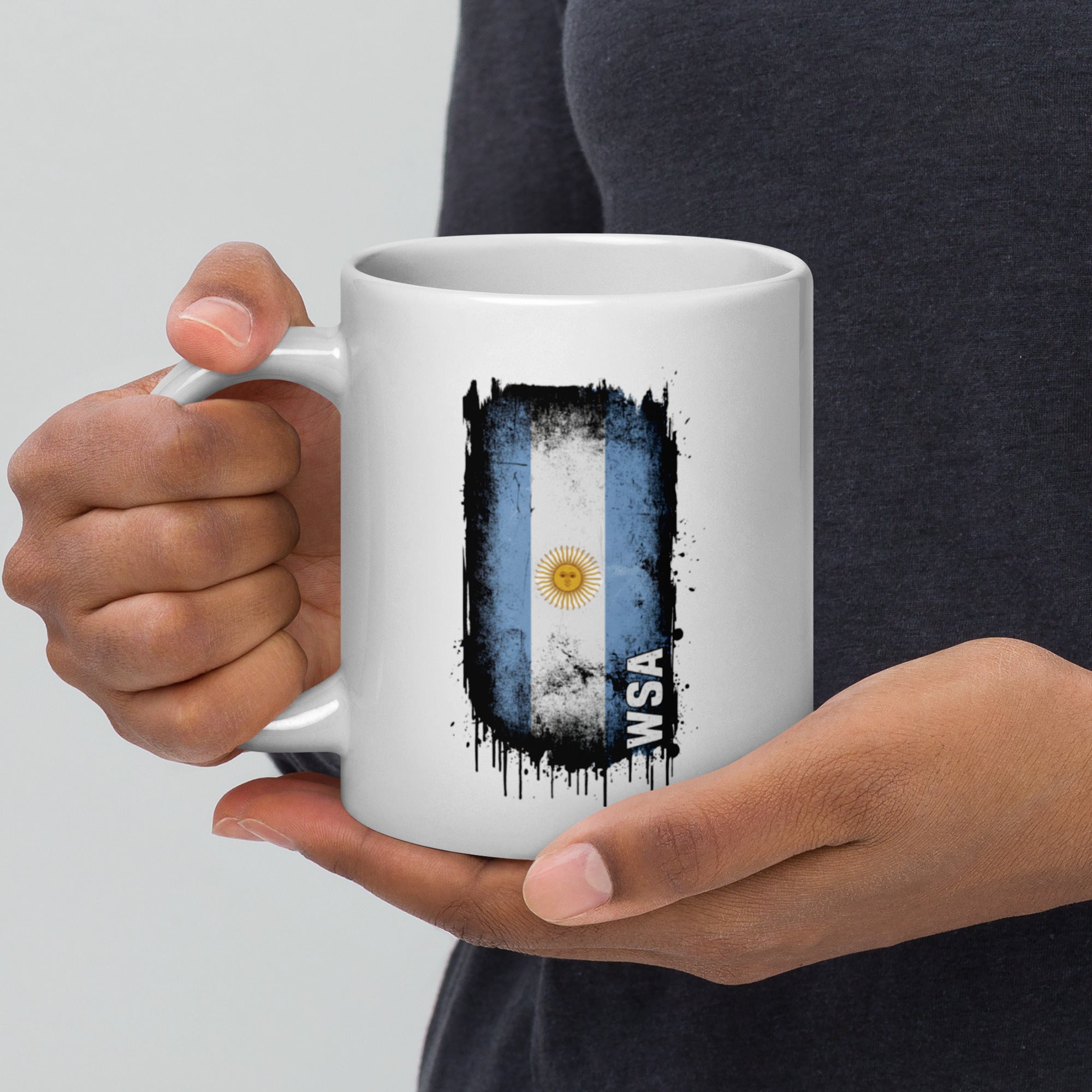 Person holding a white mug with an Argentina flag design and 'WSA' text.