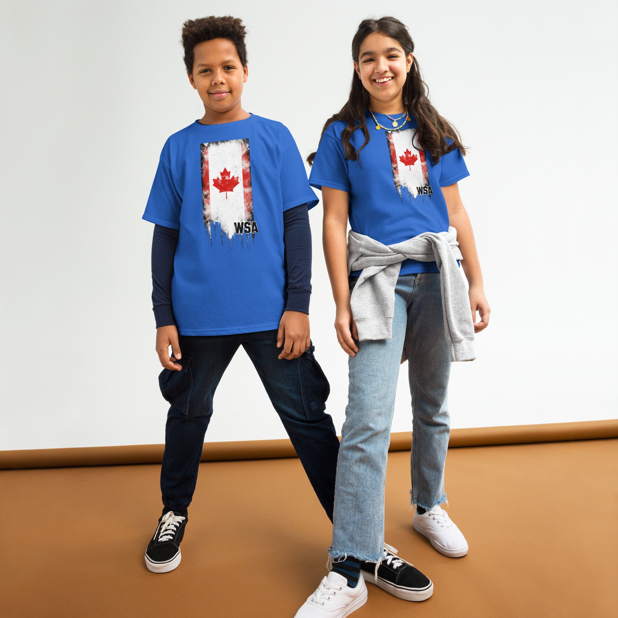 Two children wearing blue t-shirts with a map of Canada design on a plain background
